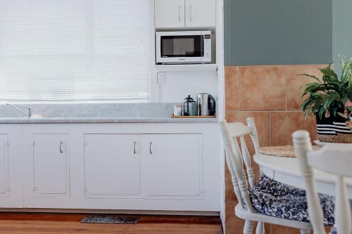 a kitchen with white cabinets and a microwave at Hokitika Beach Break in Hokitika