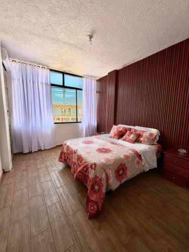 a bedroom with a bed with a floral bedspread and a window at casa del sol in Tena