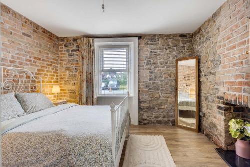 a brick walled bedroom with a bed and a mirror at Old Post Office Apartment in Monaghan