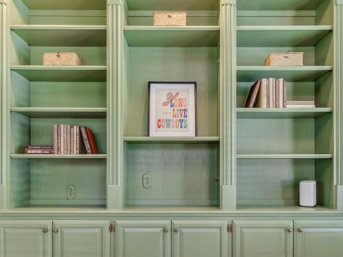 a library with green walls and white shelves with books at The Big Friendly - A family retreat, heated pool, hot tub, game room minutes away from DT OKC in Oklahoma City