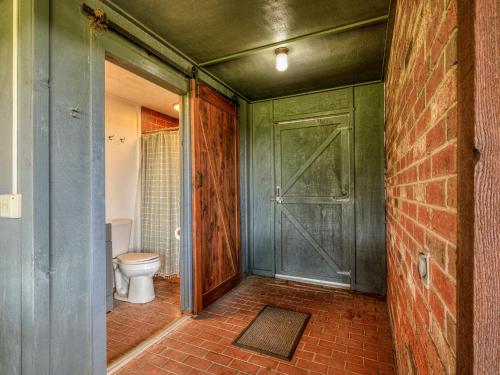 a bathroom with a toilet and a green door at The Big Friendly - A family retreat, heated pool, hot tub, game room minutes away from DT OKC in Oklahoma City