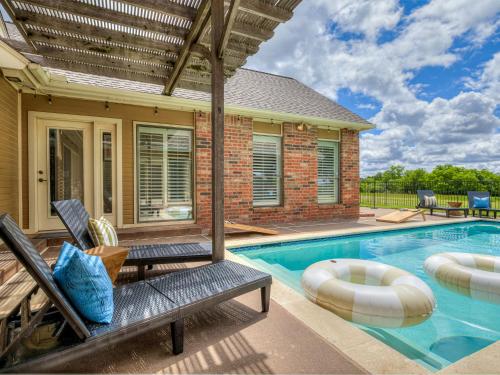 a swimming pool with chairs and a house at The Big Friendly - A family retreat, heated pool, hot tub, game room minutes away from DT OKC in Oklahoma City