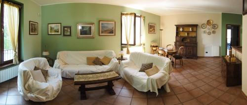 Ca' Rosa Bed & Breakfast في Malnate: غرفة معيشة بأثاث أبيض وجدران خضراء