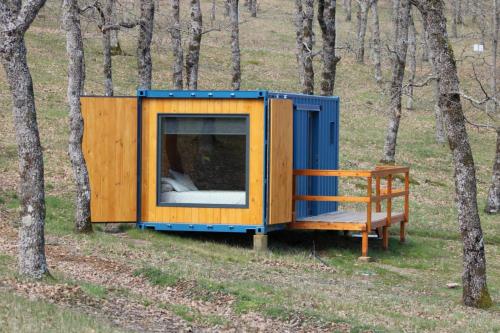 a tiny house in the woods with a bench at El Roble Glamping - Cabaña Container - Pet Friendly in Lagunilla