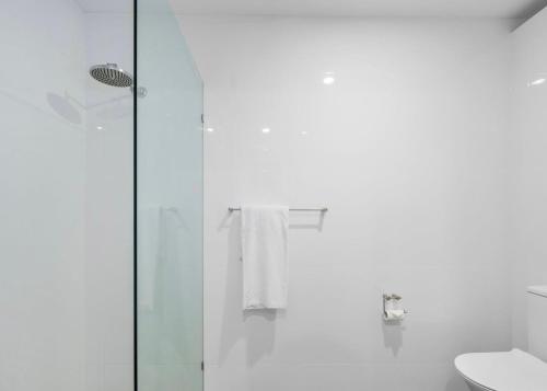a white bathroom with a shower and a toilet at Nautilus Beach Apartment 109 in Coffs Harbour