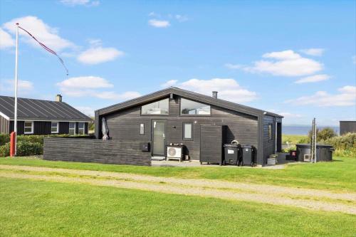 a black house on a field with a grass yard at LF12006-Handbjerg-Runddelen-6 