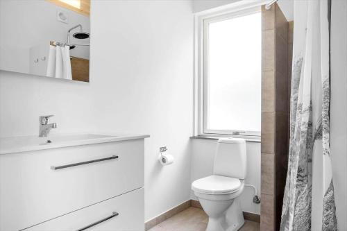 a white bathroom with a toilet and a window at LF14344-Roslev-Folvigvej-44 in Roslev
