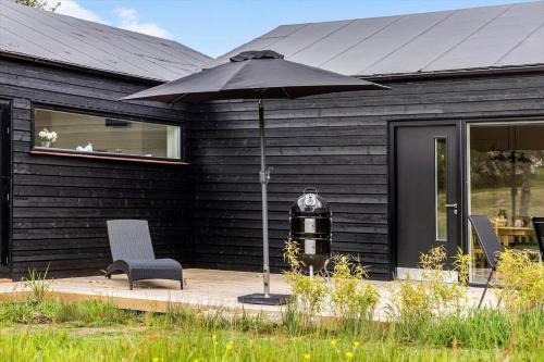 a black house with a chair and an umbrella at LF14344-Roslev-Folvigvej-44 in Roslev