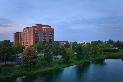 a building with a sign on it next to a river at Chicago Marriott Northwest in Hoffman Estates