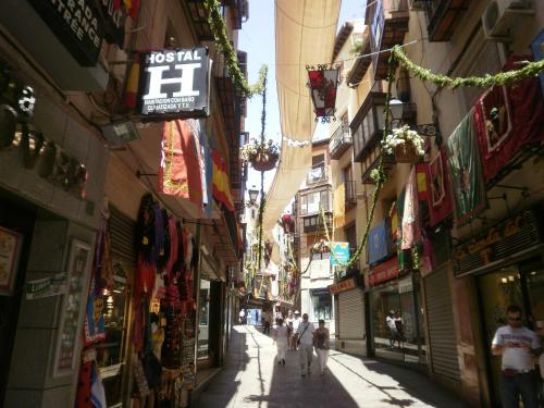 an alley with people walking down a street between buildings at Hostal la posada de Zocodover in Toledo