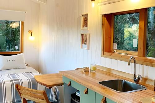 Una cocina con fregadero y una cama en una habitación. en Escapada en pareja en un rincón del bosque, en San Martín de los Andes