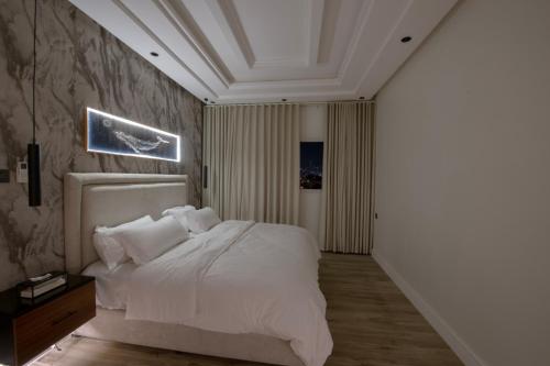 a bedroom with a bed with white sheets and pillows at شقق سكنة الرياض in Quai