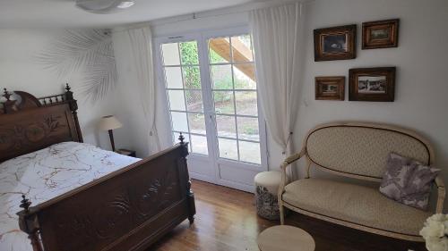 ein Schlafzimmer mit einem Bett, einem Fenster und einem Stuhl in der Unterkunft Charmant T2 avec terrasse jardin et parking privé, à 2 minutes du centre ville ! in Villeneuve-sur-Lot