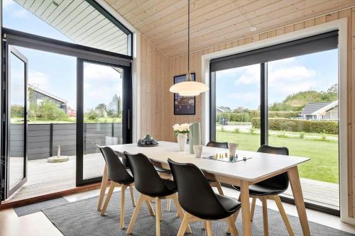 a dining room with a table and chairs and large windows at OH419-Hadsund-Halvrebene-60 in Hadsund