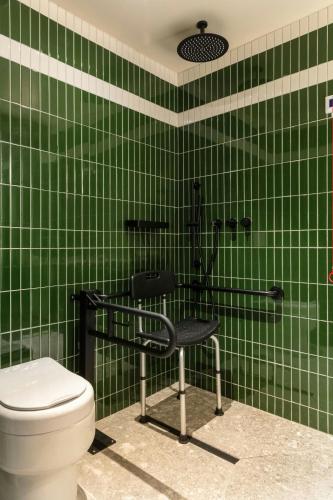 a green tiled bathroom with a chair and a toilet at Salitre Hotel, Sonder by Marriott Bonvoy in Málaga