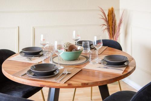 a wooden table with glasses and a bowl of food on it at Nouveau - Vue panoramique Vosges - 90m moderne et Cocoon - Parking et Netflix in Mulhouse