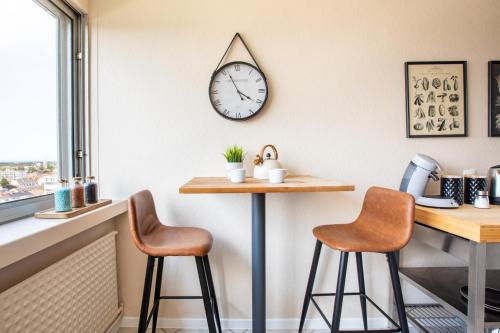 a kitchen with two bar stools and a clock on the wall at Nouveau - Vue panoramique Vosges - 90m moderne et Cocoon - Parking et Netflix in Mulhouse