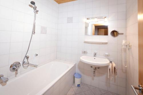 a white bathroom with a tub and a sink at Ferienhaus Auer in Nauders