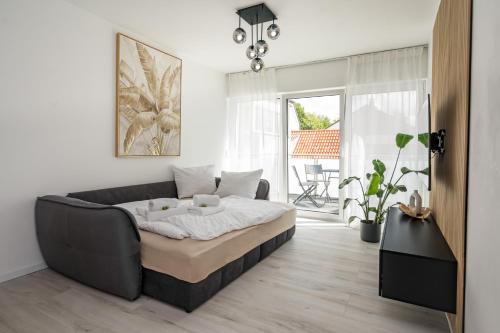 a living room with a bed and a couch at Moderne Wohnung mit Balkon - nahe Kurpark & Messezentrum in Bad Salzuflen