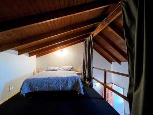 a bedroom with a bed in a room with wooden ceilings at Genoveva, descanso y calma in Neuquén
