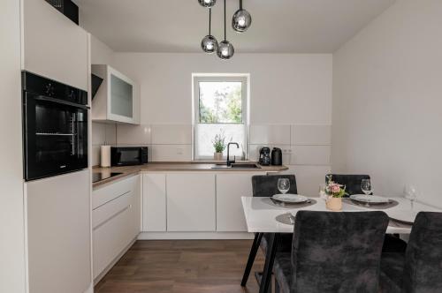 a kitchen with white cabinets and a table with chairs at Moderne Wohnung mit Balkon - nahe Kurpark & Messezentrum in Bad Salzuflen