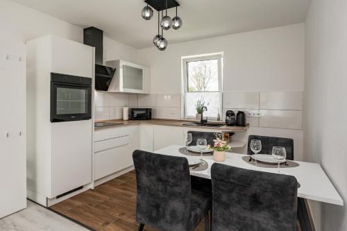 a white kitchen with a table and chairs at Moderne Wohnung mit Balkon - nahe Kurpark & Messezentrum in Bad Salzuflen