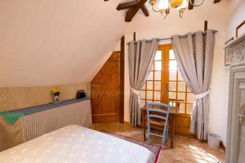 a bedroom with a bed and a table and a window at Le Moulin du Cluzeau in Thollet