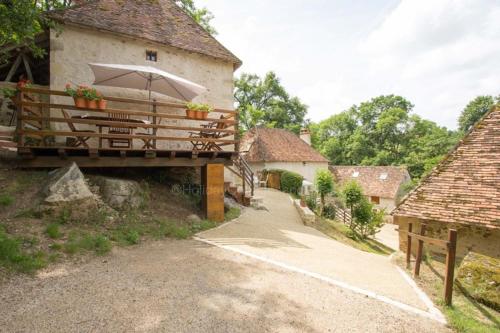 a building with a balcony with an umbrella at Le Moulin du Cluzeau in Thollet