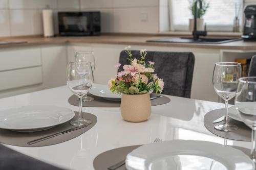 a table with glasses and a vase with flowers on it at Moderne Wohnung mit Balkon - nahe Kurpark & Messezentrum in Bad Salzuflen