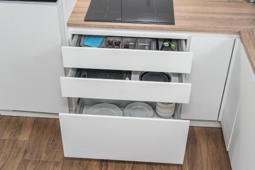 an open kitchen drawer with white drawers at Moderne Wohnung mit Balkon - nahe Kurpark & Messezentrum in Bad Salzuflen