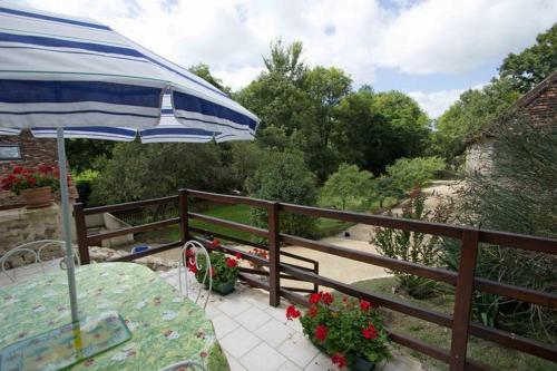 a patio with a table and an umbrella at Le Moulin du Cluzeau in Thollet