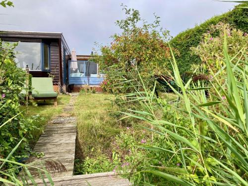 a wooden path through a garden with a green chair at Charming Bungalow in Anjum, Netherlands with Lake Views in Anjum