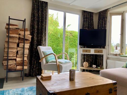 a living room with a tv and a chair and a table at Charming Bungalow in Anjum, Netherlands with Lake Views in Anjum