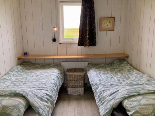 two beds in a small room with a window at Charming Bungalow in Anjum, Netherlands with Lake Views in Anjum