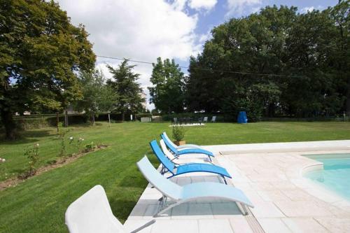 a group of lounge chairs next to a swimming pool at Le Moulin du Cluzeau in Thollet