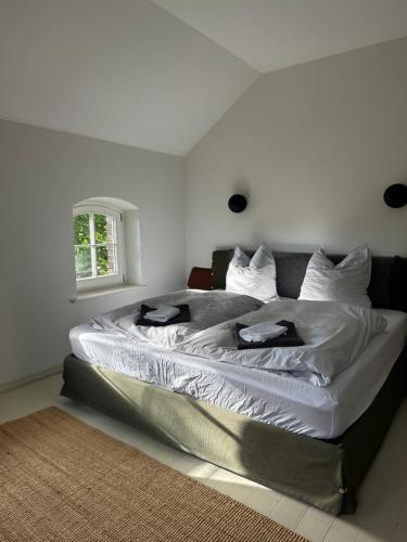 a bedroom with a large bed with white sheets and a window at Design Villa Uckermark mit riesigem Garten in Ferdinandshof