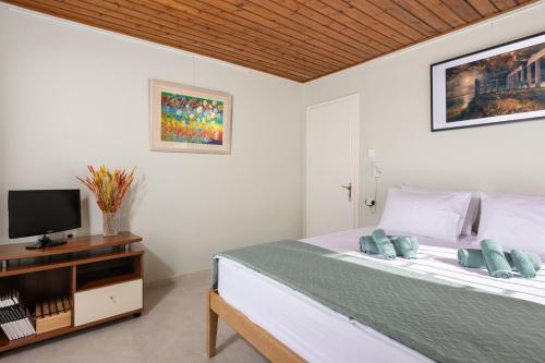 a white bedroom with a bed and a tv at Art Sounion, Seafront Elegance in Sounio