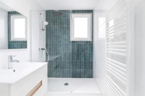 a white bathroom with a shower and a sink at Les Appartements Chambon in Sarlat-la-Canéda