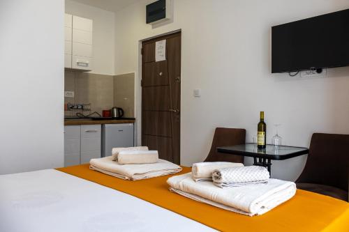 a room with two beds and a table and a tv at Sienna Apartments Budva in Budva