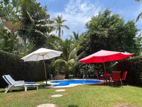 曼萨尼约La Casa del Mar, Club Santiago with a private pool的游泳池旁边的两把遮阳伞和椅子