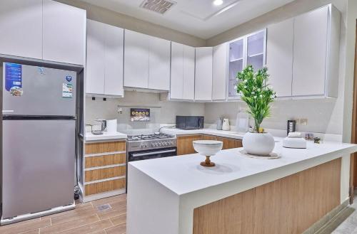a kitchen with white cabinets and a white refrigerator at شقة بثلاث غرف فاخرة وبطراز أنيق in Jeddah