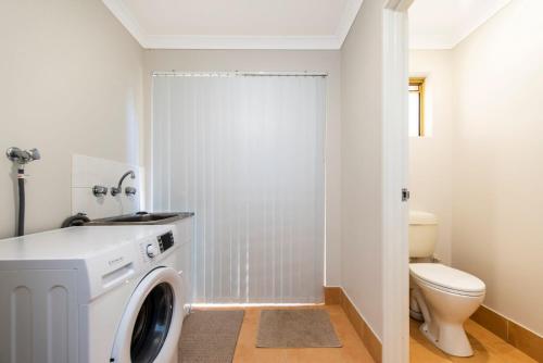 a bathroom with a washing machine and a toilet at Waves And Moore - Beautifully presented home in Guilderton