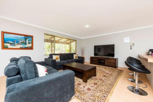 a living room with a blue couch and a tv at Waves And Moore - Beautifully presented home in Guilderton