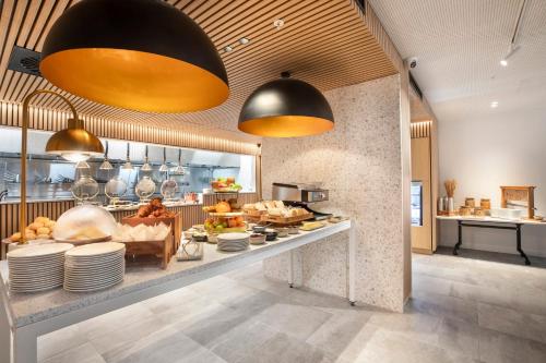 a restaurant with a counter with plates and food at Holiday Inn Melbourne Bourke Street Mall by IHG in Melbourne