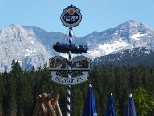 a sign for a restaurant with mountains in the background at Winklmoos Sonnenalm in Reit im Winkl