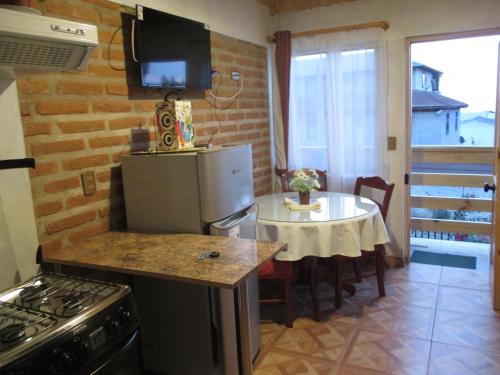 a small kitchen with a table and a refrigerator at Hostal Julia in El Quisco