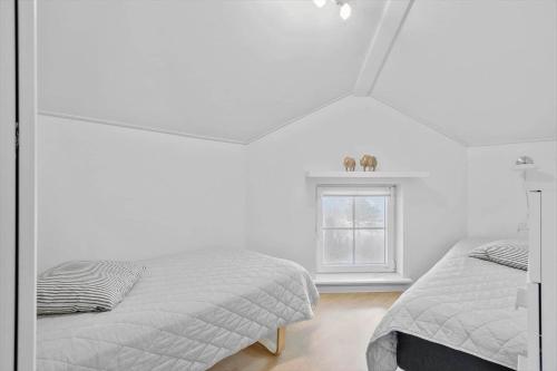 a white bedroom with two beds and a window at FY213-Bogense-Vestre-Engvej-138-1-th in Bogense