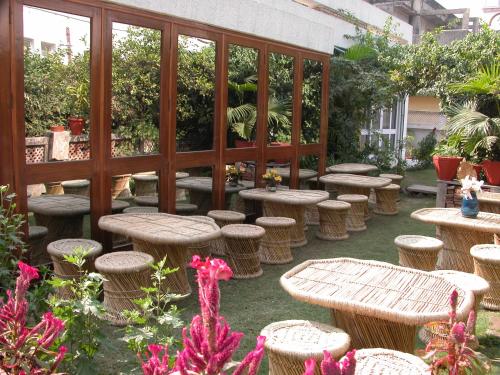 a group of tables and stools in a garden at Petite Homestays in New Delhi