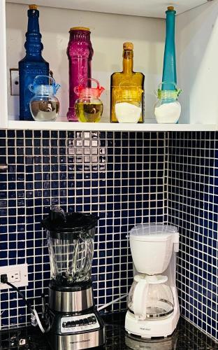 a shelf with different colored bottles and a blender at Avila apartment in Caracas