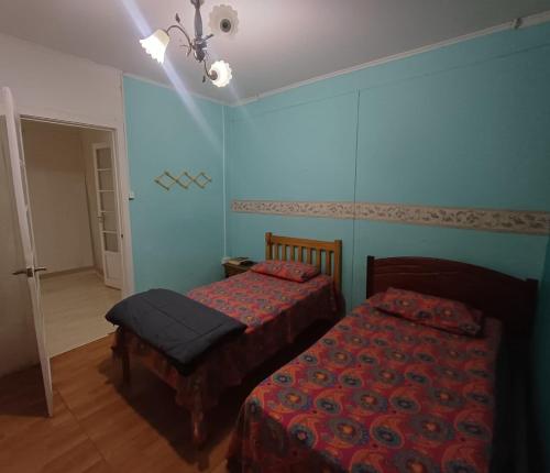 two beds in a bedroom with blue walls at Casa Central in Punta Arenas